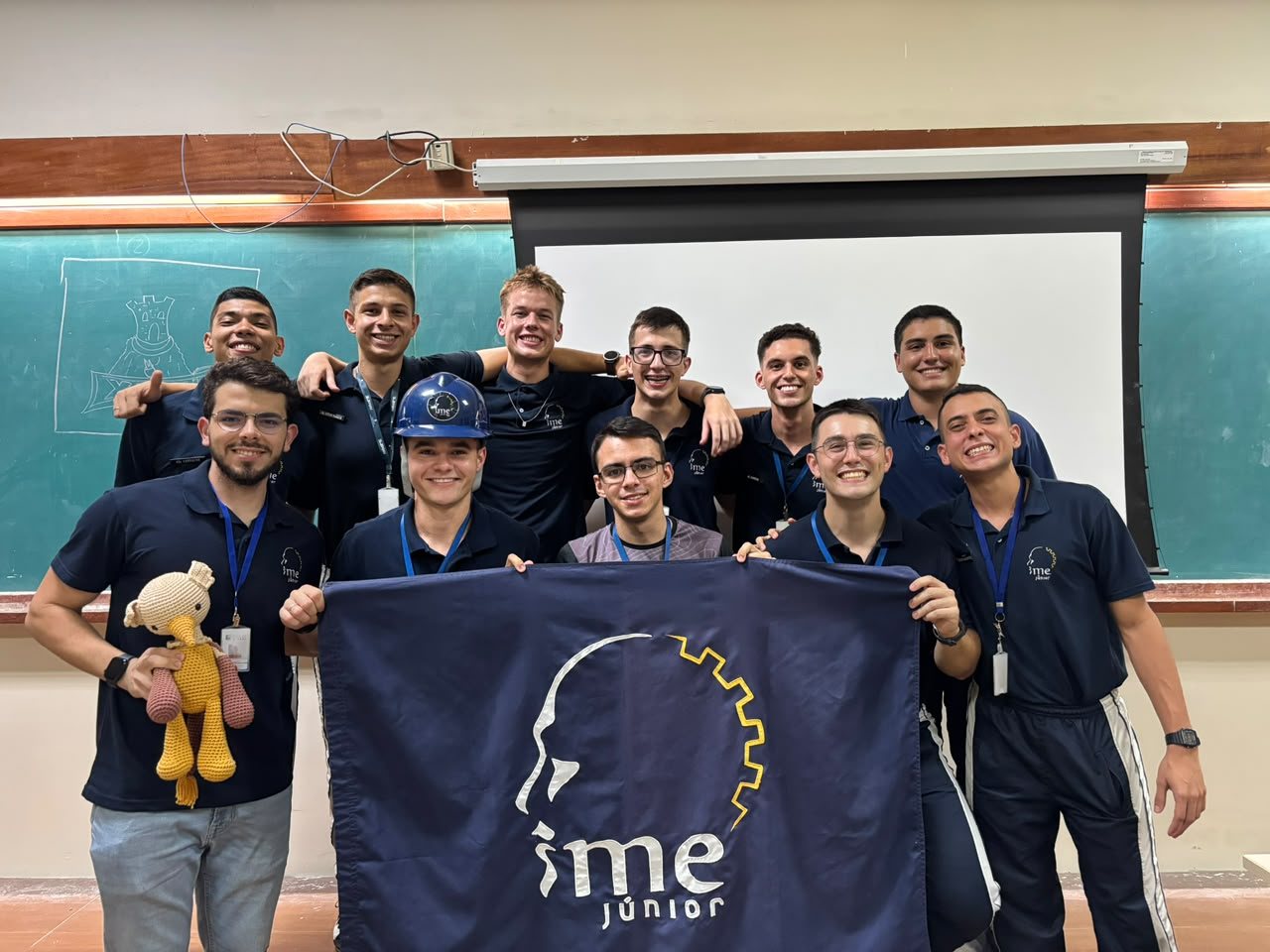 Membros da IME Júnior segurando a bandeira da empresa